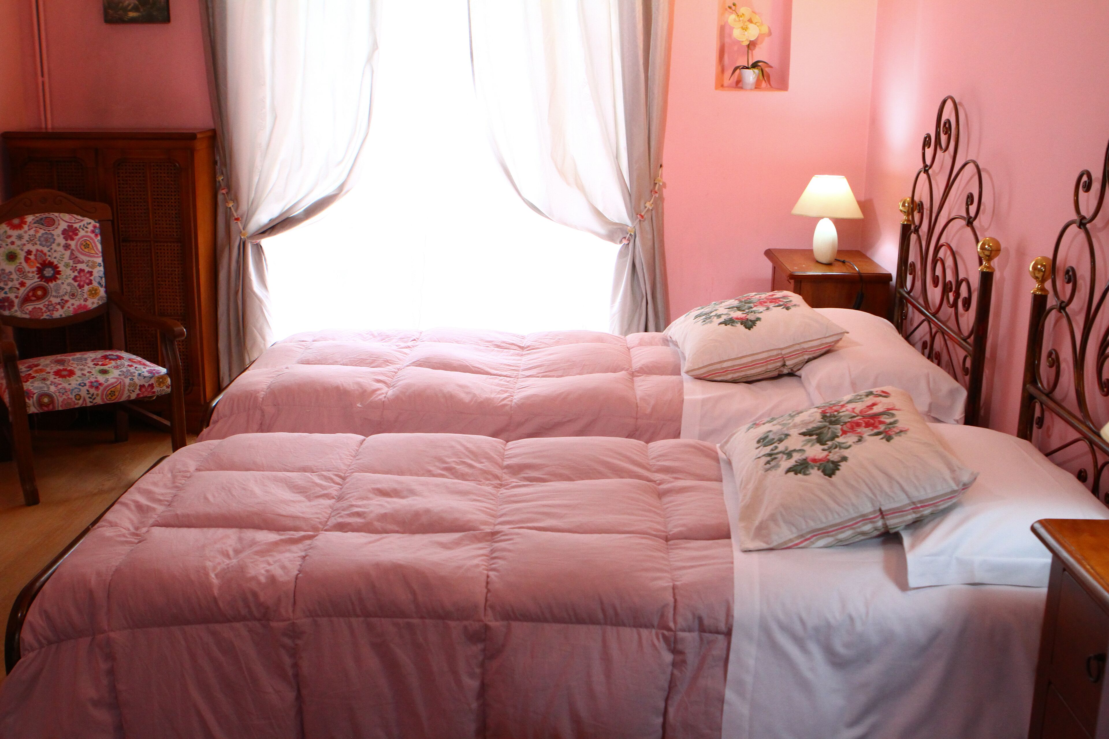 A bedroom with a large bed, a chair, a nightstand, and a lamp.