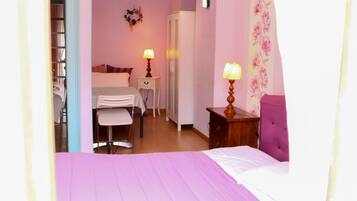 A bedroom with a bed, a desk, a chair, a wardrobe, and two lamps.