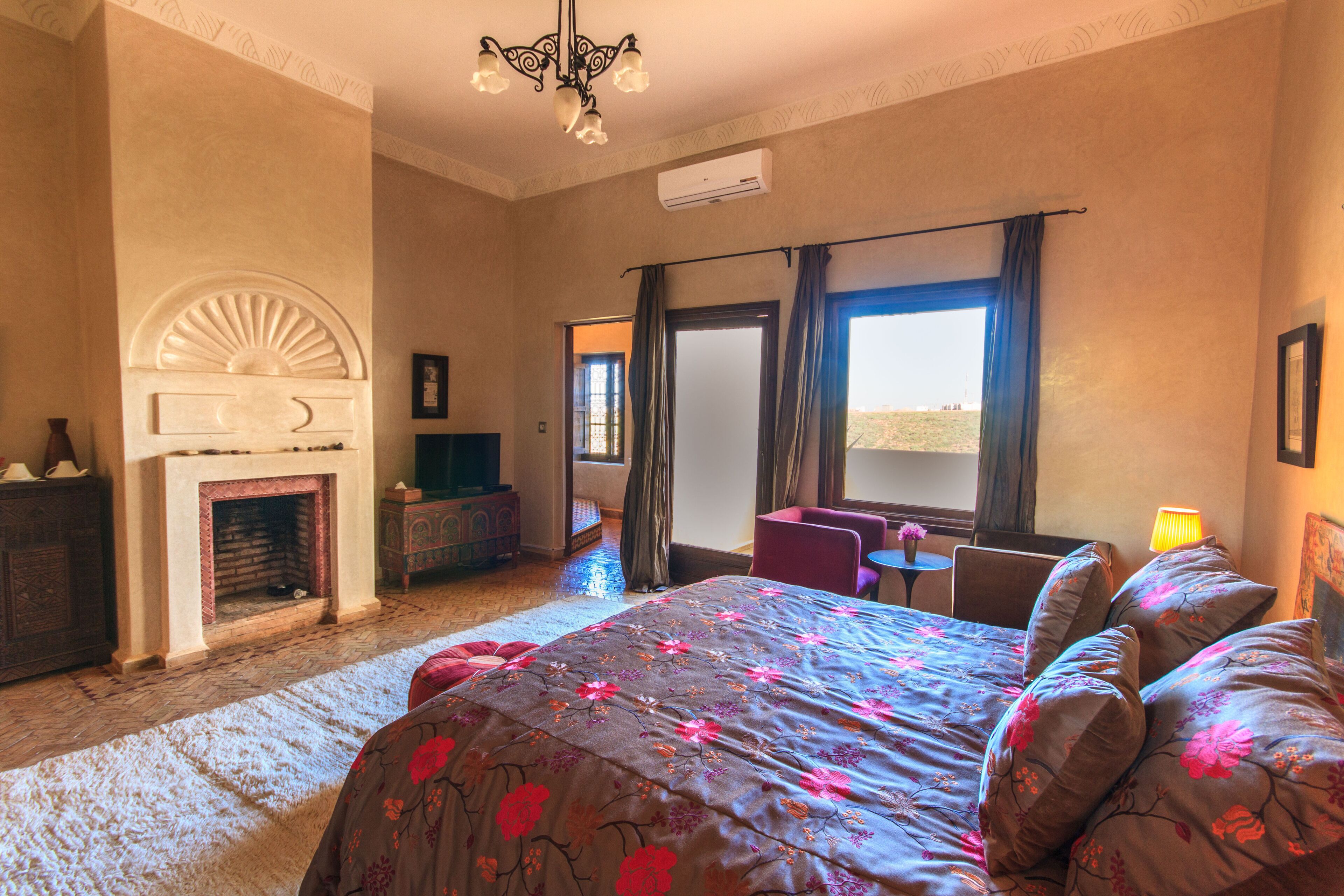 Un dormitorio con una cama grande, una chimenea, un escritorio y vistas al desierto.