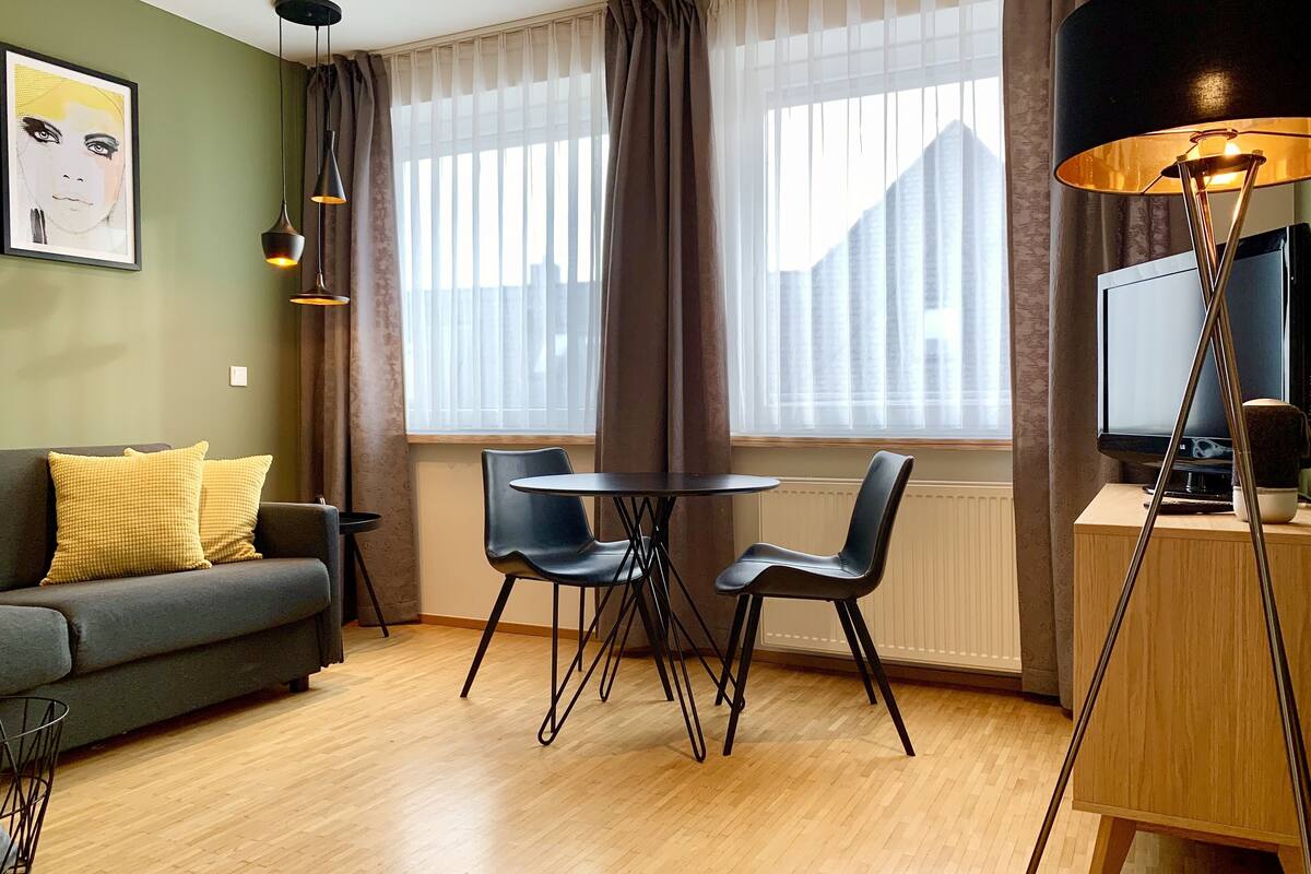 Een moderne woonkamer met een bank, twee stoelen, een salontafel, een televisie en een lamp.