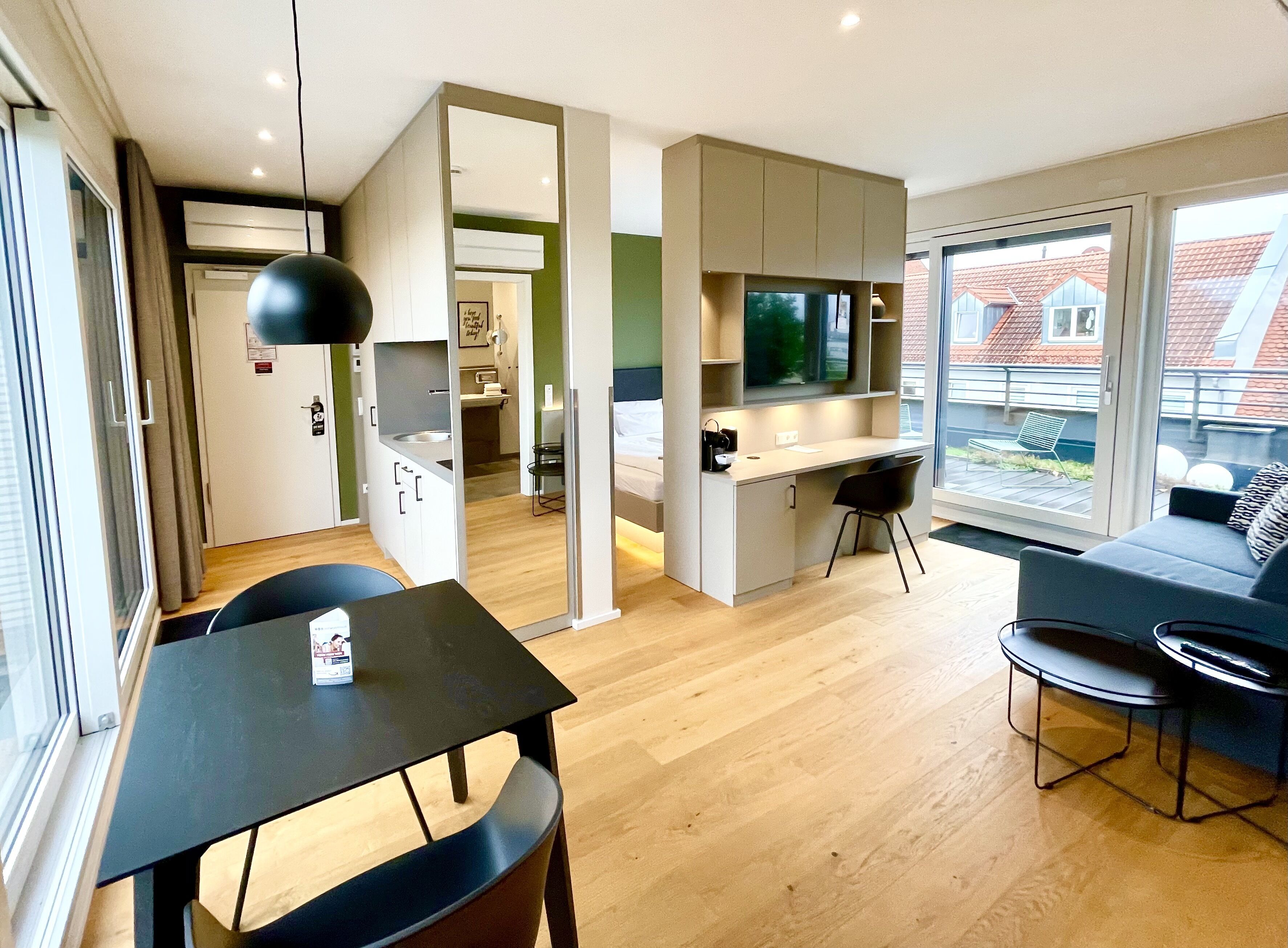 Un apartamento moderno con comedor, kitchenette, sala de estar con sofá y televisor.