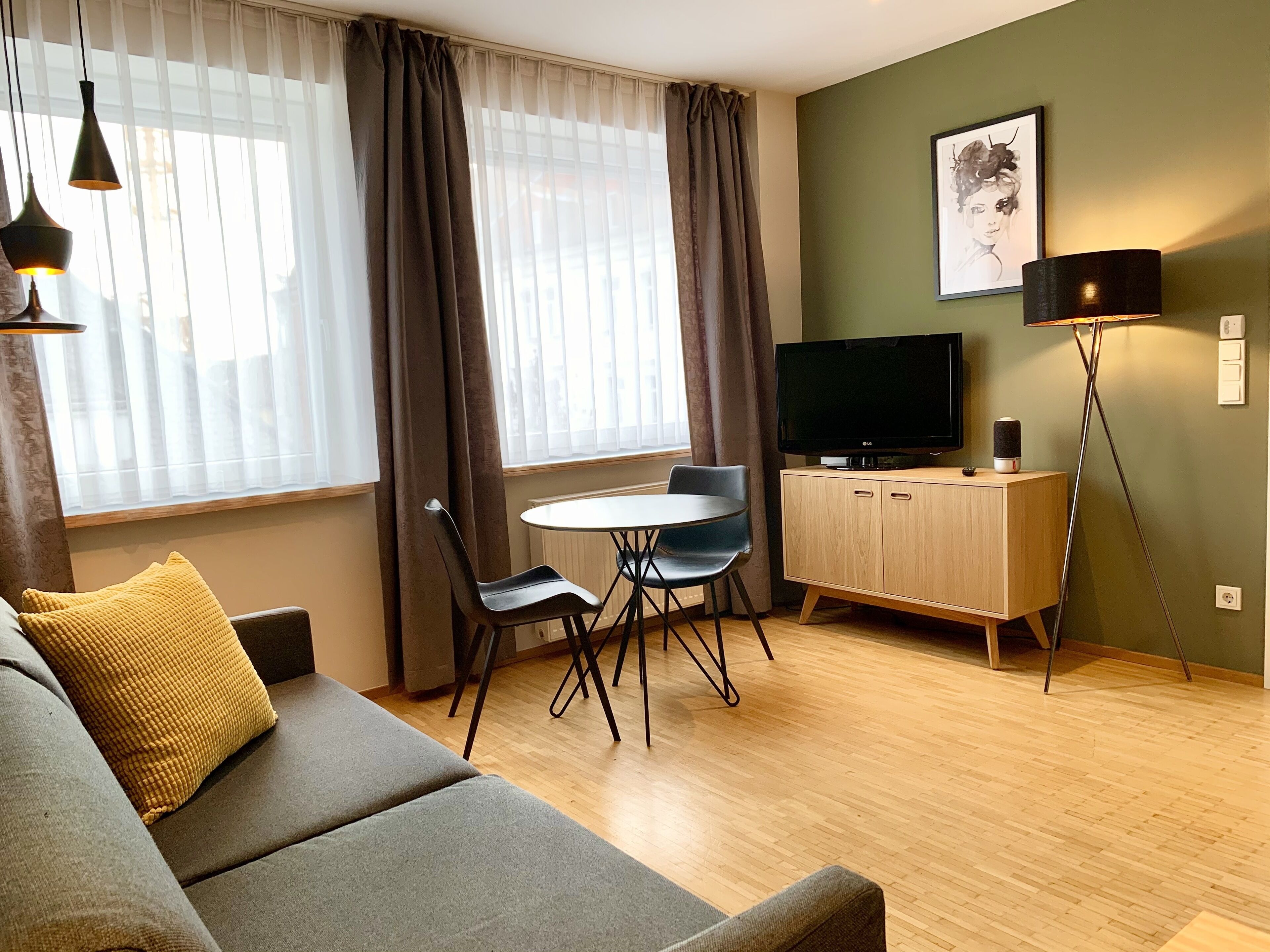 En moderne stue med sofa, spisebord med stole, fjernsyn og gulvlampe.