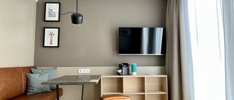A modern living room with a sofa, a coffee table, a TV, and a bookshelf.