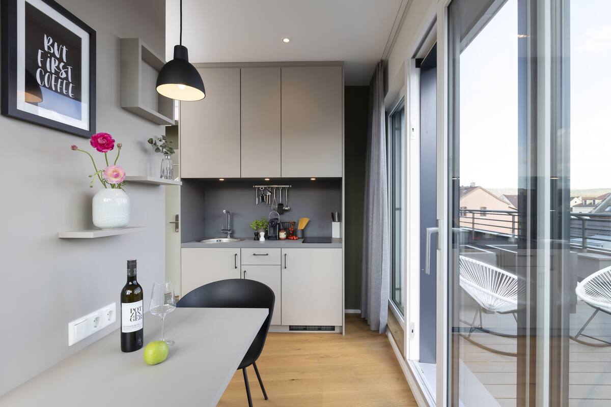 Een moderne keuken met witte kasten, een eettafel en een fles wijn.