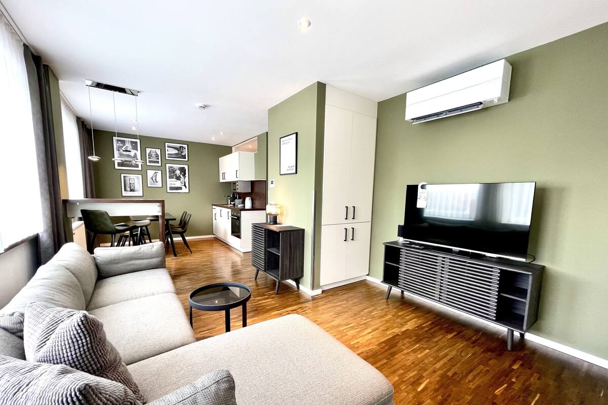 Een moderne woonkamer met een bank, een eethoek en een keuken op de achtergrond.