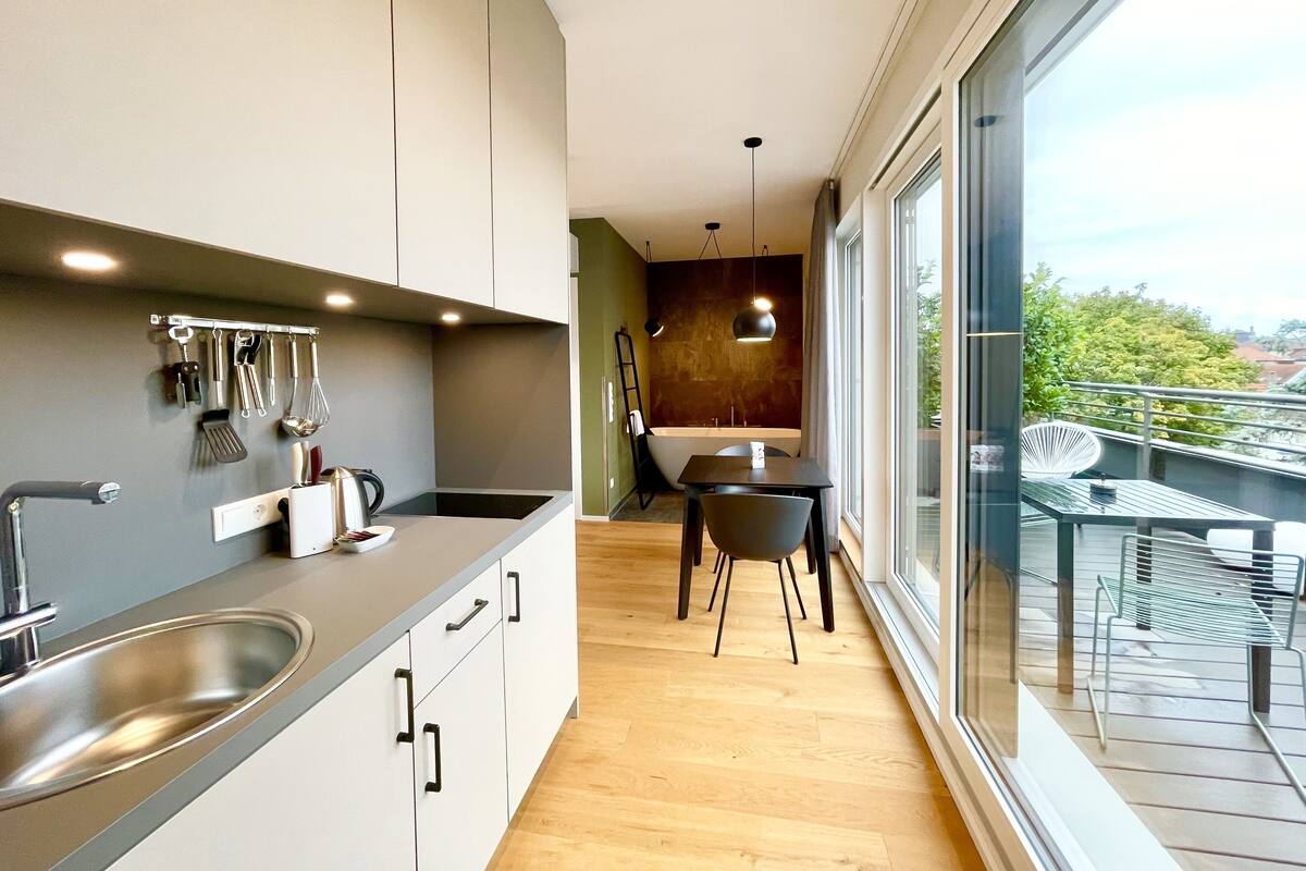 Een moderne keuken met een ingebouwde spoelbak, roestvrijstalen apparatuur en een eethoek met tafel en stoelen.