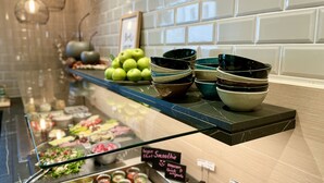 Mostrador de buffet con diferentes alimentos y recipientes.