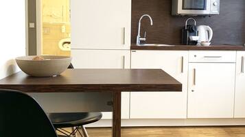 Una cocina moderna con armarios blancos, una mesa de comedor de madera y sillas negras.