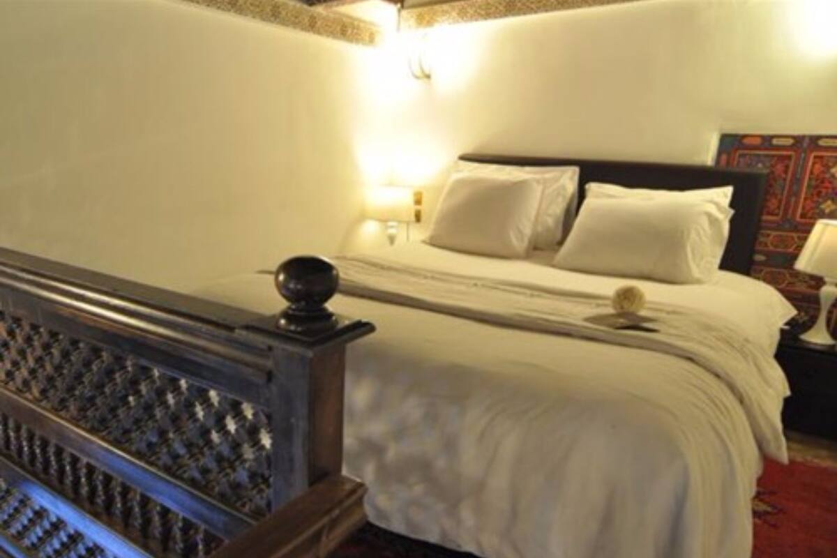 Una habitación de hotel con cama, mesita de noche y un panel decorativo en la pared.