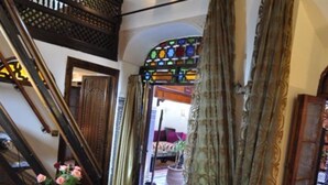 A staircase with ornate woodwork, a stained glass window, and a checkered floor pattern. - Riad Adarissa (Fes)