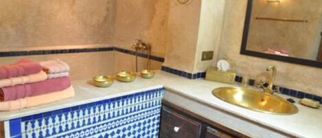 A bathroom with a sink, mirror, towel rack, and decorative tiles.