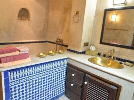Casa de banho com lavatório, espelho, porta-toalhas e azulejos decorativos.
