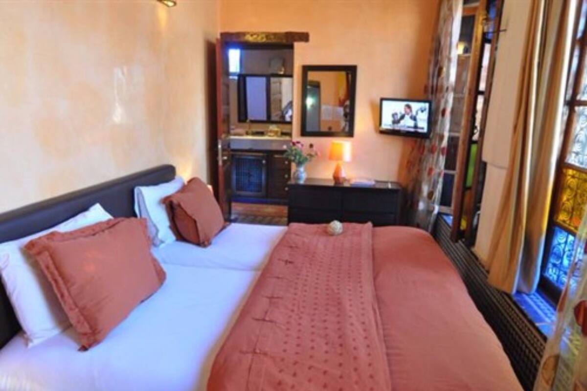 Habitación de hotel con cama, cómoda, espejo y televisor.