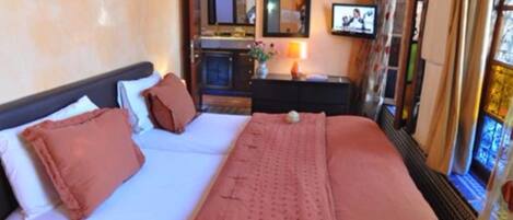 Habitación de hotel con cama, cómoda, espejo y televisor.
