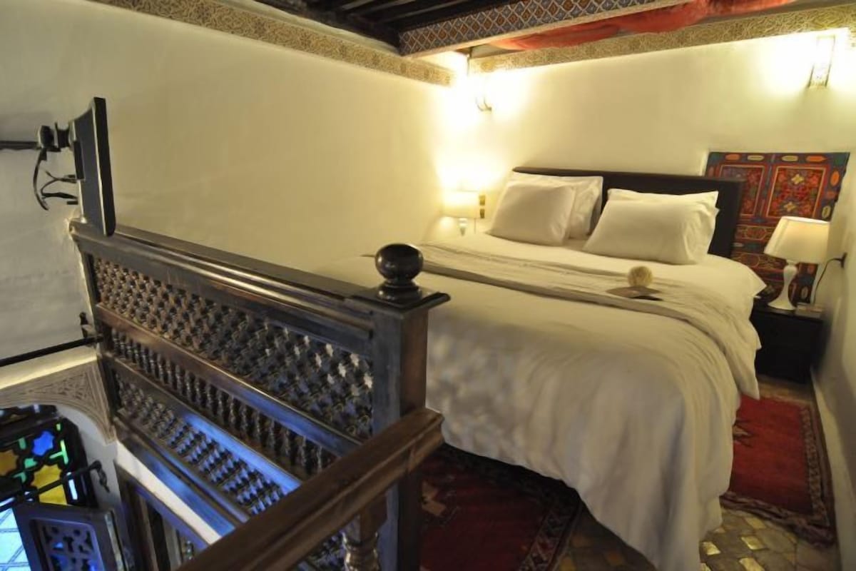 Ein Hotelzimmer mit einem Bett, einem Nachttisch, einer Lampe und einem dekorativen Kopfteil.