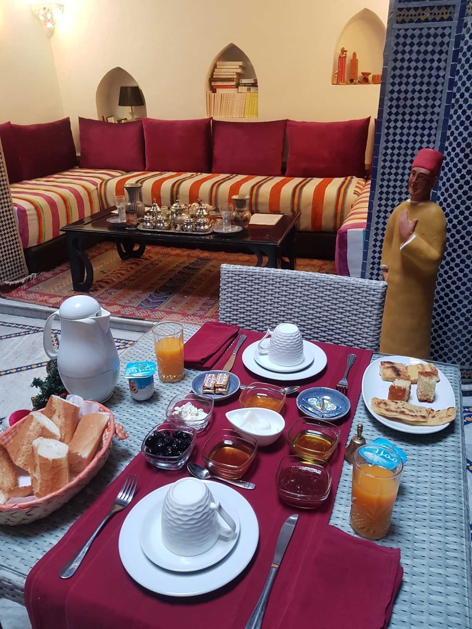 Comedor con una mesa dispuesta para el desayuno, incluyendo pan, pasteles y bebidas.