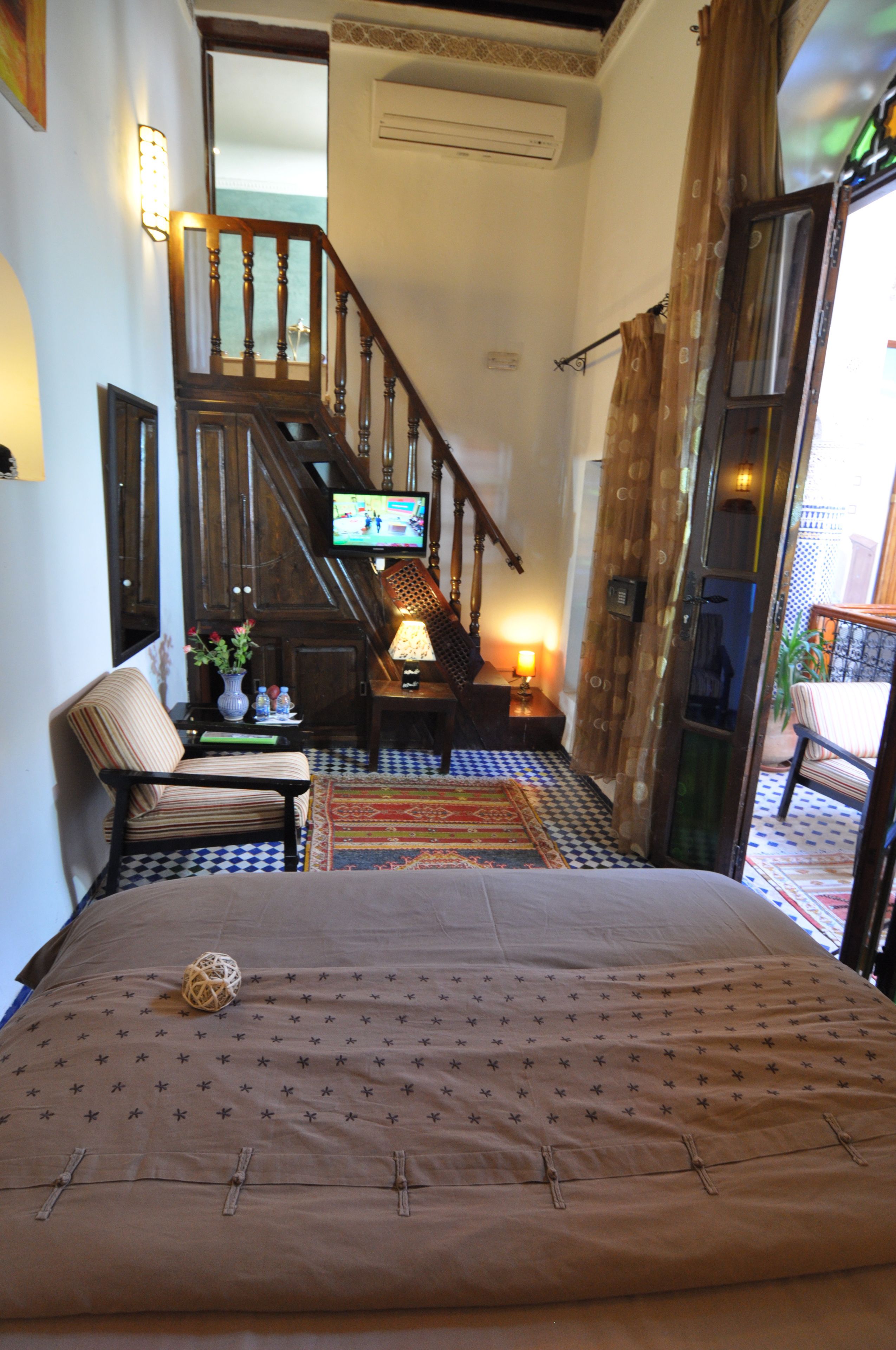 Ein Schlafzimmer mit Bett, Sessel, Fernseher, Treppe und Blick ins Freie.
