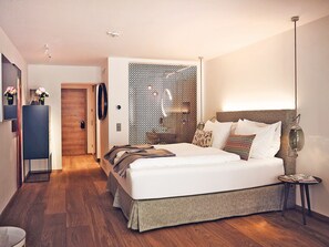 Habitación de hotel moderna con una cama grande, una mesita de noche, una lámpara y un panel decorativo en la pared.