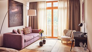 A modern living room with a sofa, armchair, and a small table with glasses and a bottle. - TAUROA Seehotel Grundlsee (Grundlsee)