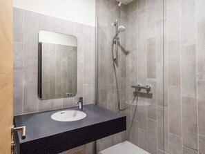 Een badkamer met een wastafel, spiegel en douche.