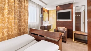 Ein Hotelzimmer mit Bett, Schreibtisch, Stuhl, Fernseher und Spiegel.