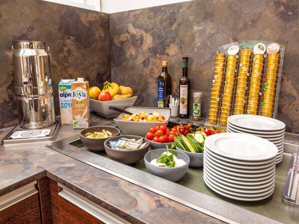 A buffet setup with various food items, beverages, and condiments.