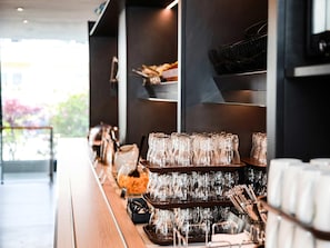 Uma área de bar com diversos conjuntos de copos e utensílios.
