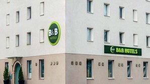 Ein Bed & Breakfast Hotel mit moderner Fassade, zahlreichen Fenstern und einem grünen Schild.