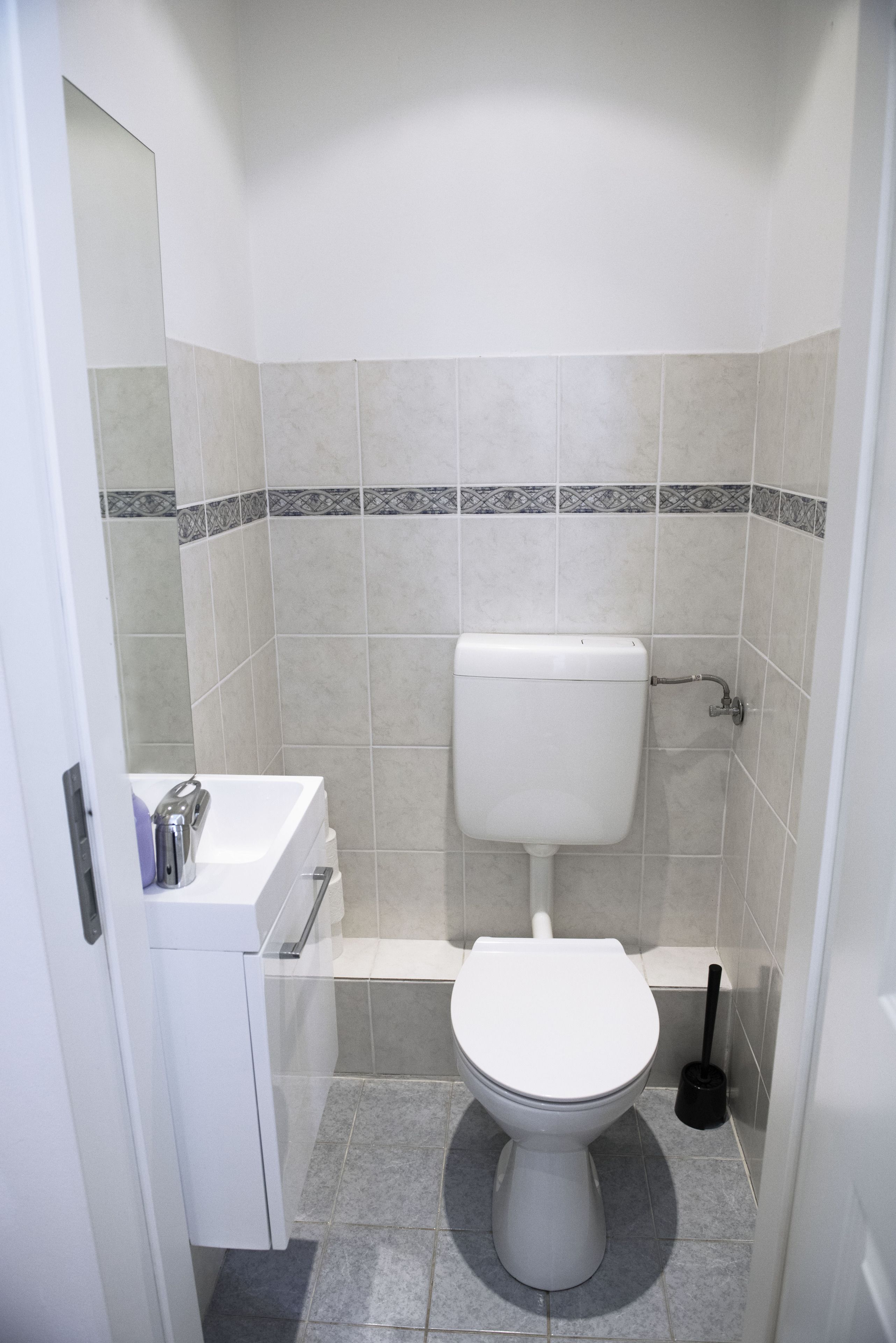 A small, clean bathroom with a toilet, sink, and mirror.