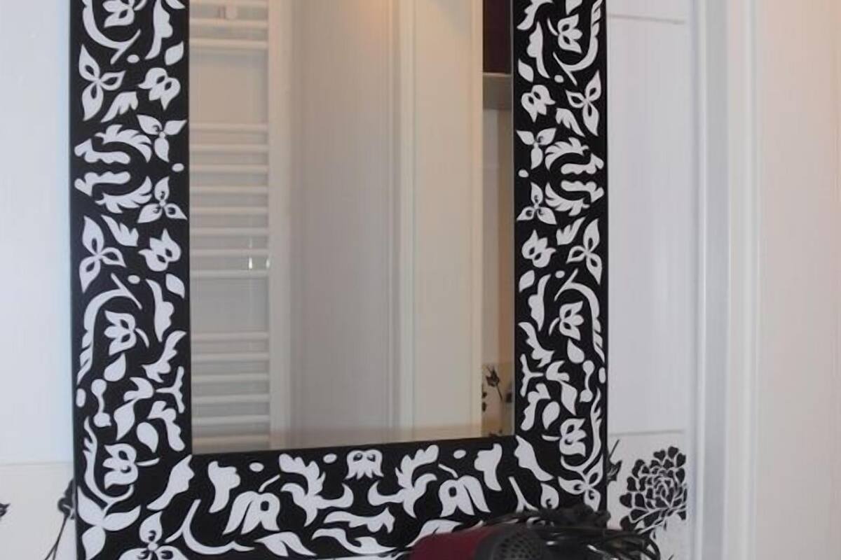 Un baño con un espejo decorativo, un lavabo y una estantería con artículos de aseo.