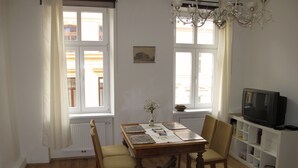 A room with a wooden table, two chairs, a television, and a chandelier. - Old Vienna Apartments (Vienna)
