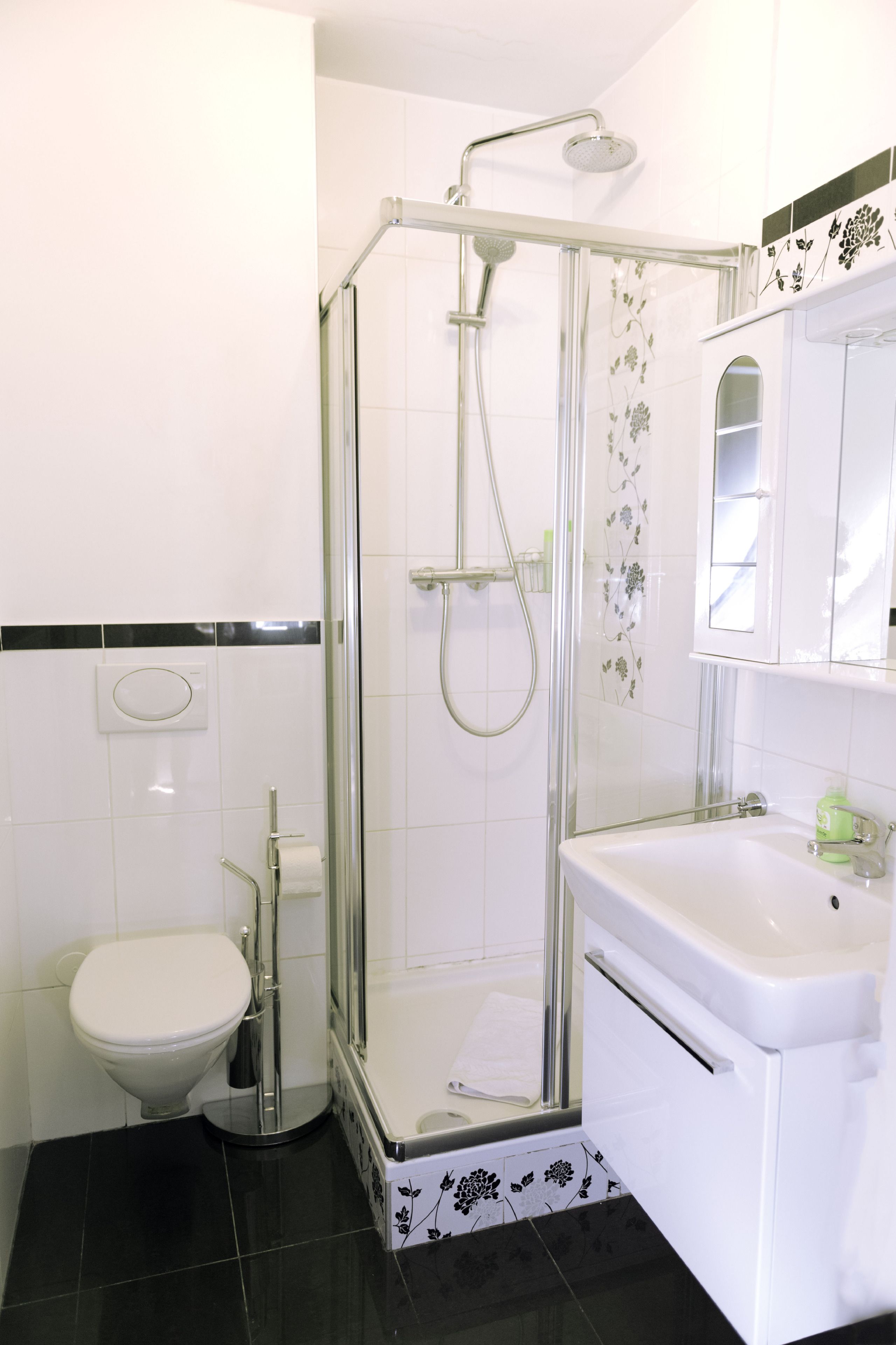 A bathroom with a glass-enclosed shower, a toilet, and a sink.