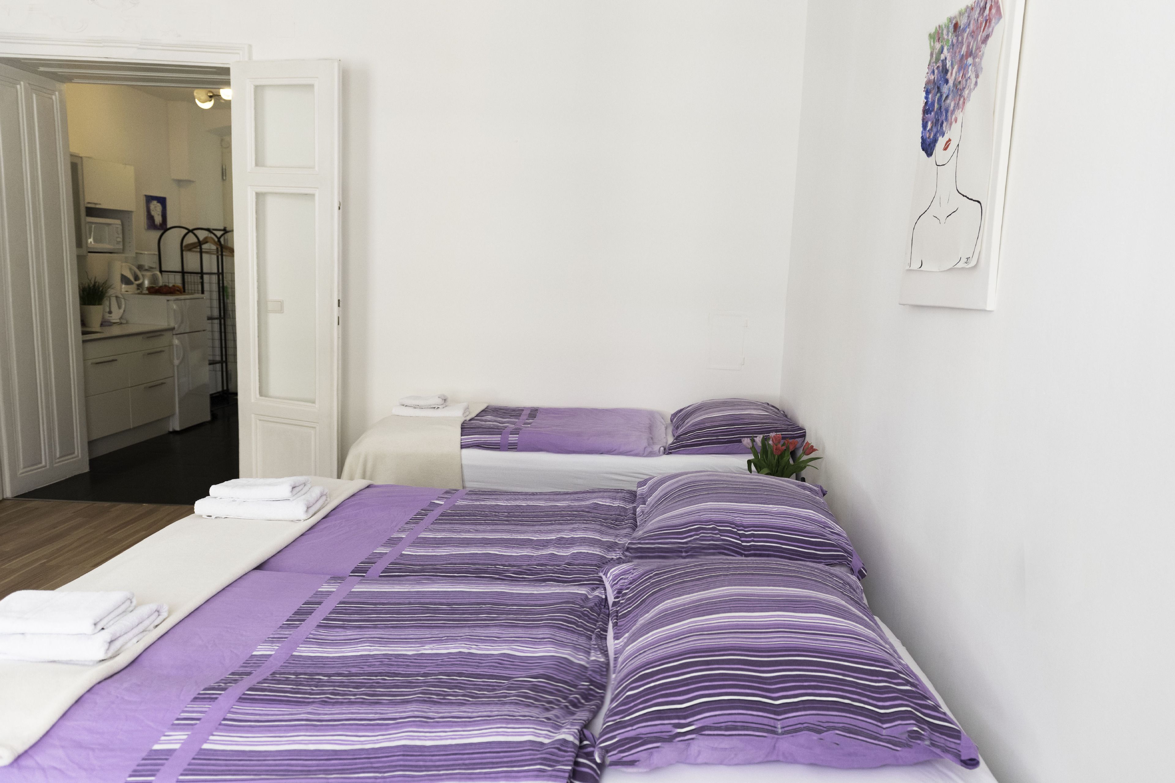 A hotel room with two beds, a kitchenette, and a bathroom visible through an open door.