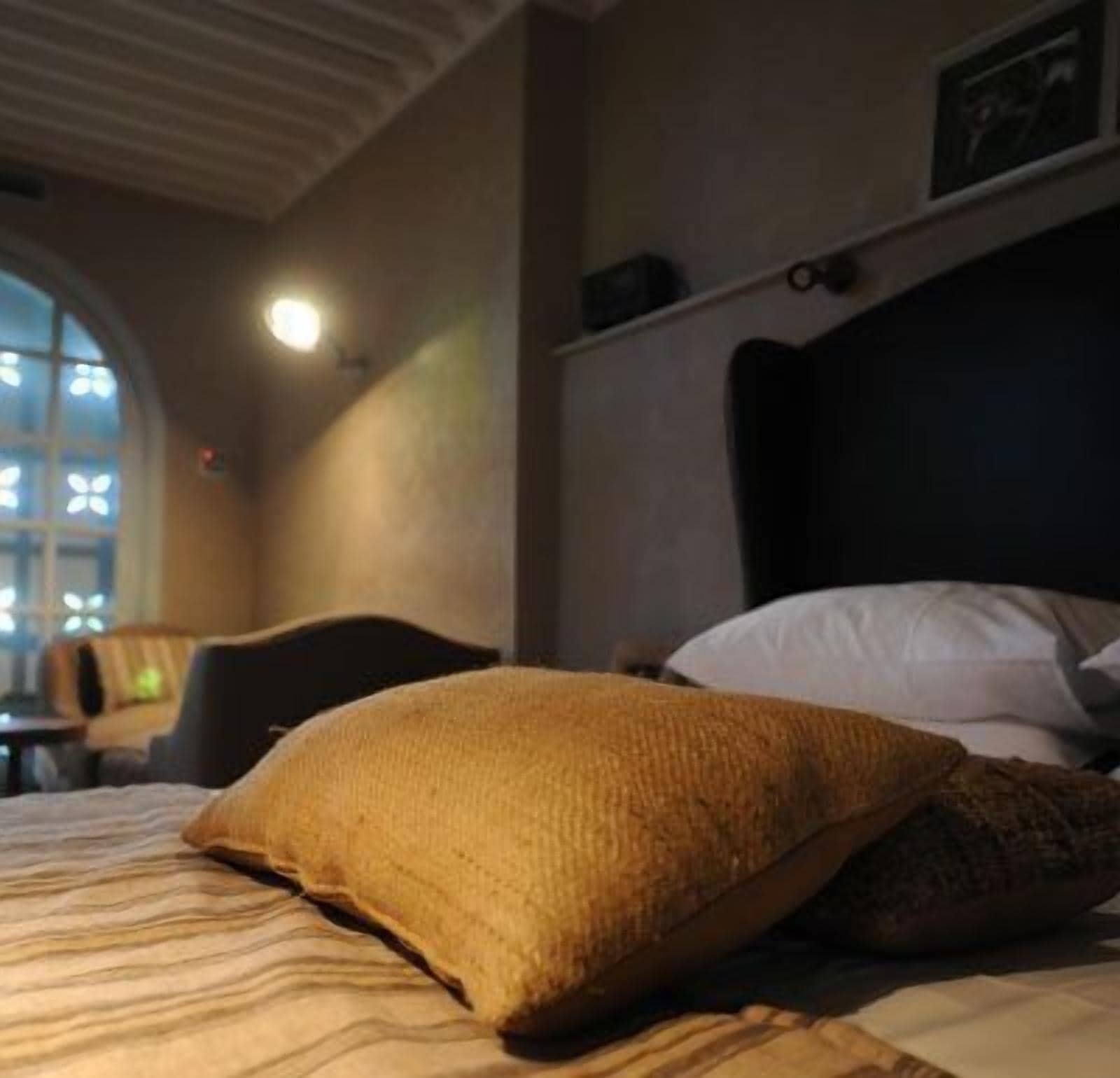A hotel room with a bed, a window with a view, and a wall-mounted shelf.