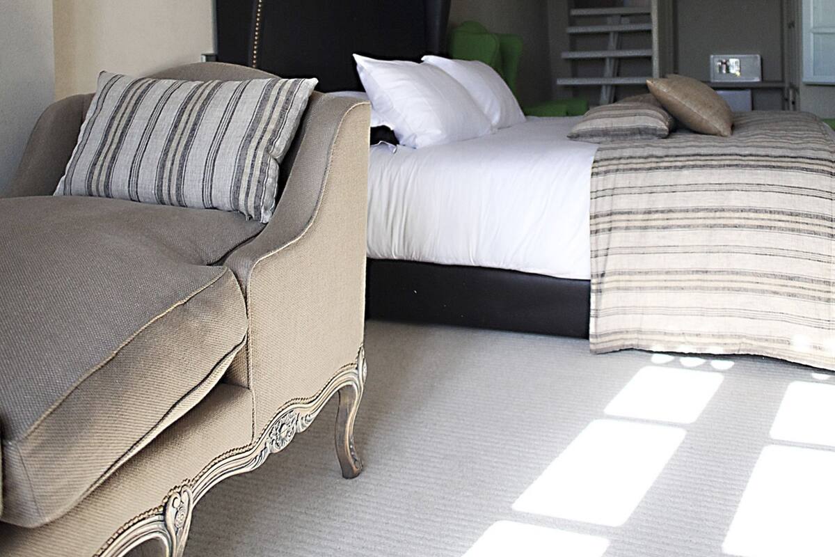 Un dormitorio con una cama, un sofá y una escalera que lleva a un nivel superior.