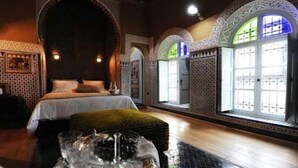 A room with a bed, a large mirror, and a window with patterned glass.