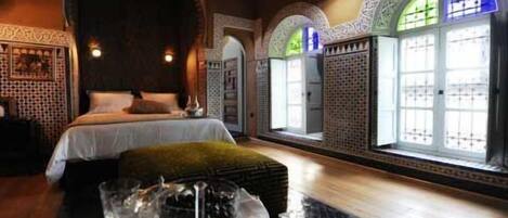 Una habitación con una cama, un espejo grande y un ventanal con vidrio decorativo.