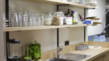 A modern kitchen with wooden cabinets, a countertop, a sink, and various kitchen items like glassware and jars.