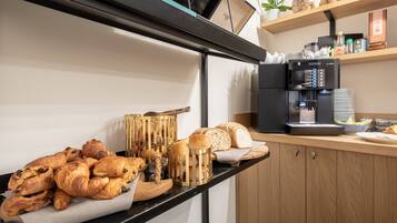 Un plan de travail de cuisine avec une machine à café, des bocaux d’épices et diverses pâtisseries.