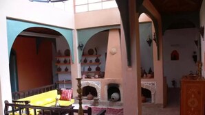 A traditional interior with a bed, a table with a lamp, and a fireplace. - Douar des Oliviers (Ounagha)