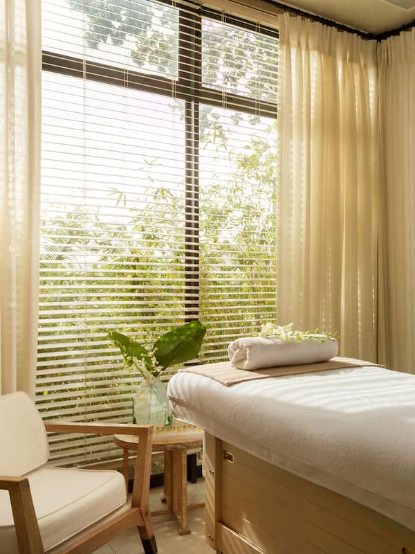 Relax in a serene spa room with a single bed, a small table, and a potted plant.