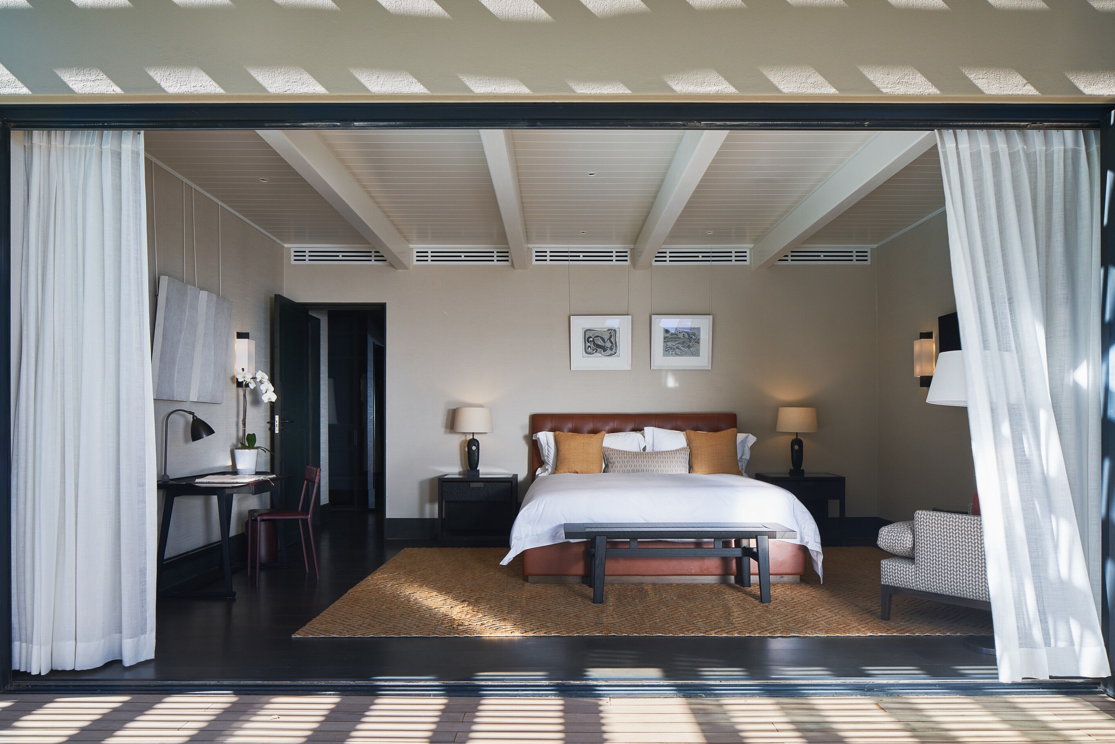 A bedroom with a large bed, bedside tables, a desk, and a chair.