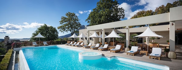 Una piscina al aire libre, sombrillas, sillones reclinables de piscina