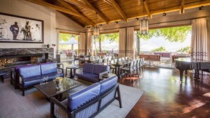 A spacious indoor area with wooden ceilings, leather sofas, dining tables, and a grand piano. - Delaire Graff Lodges & Spa (Stellenbosch)