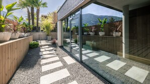 Un patio moderno al aire libre con un sendero de grava, plantas en macetas y una valla de madera.