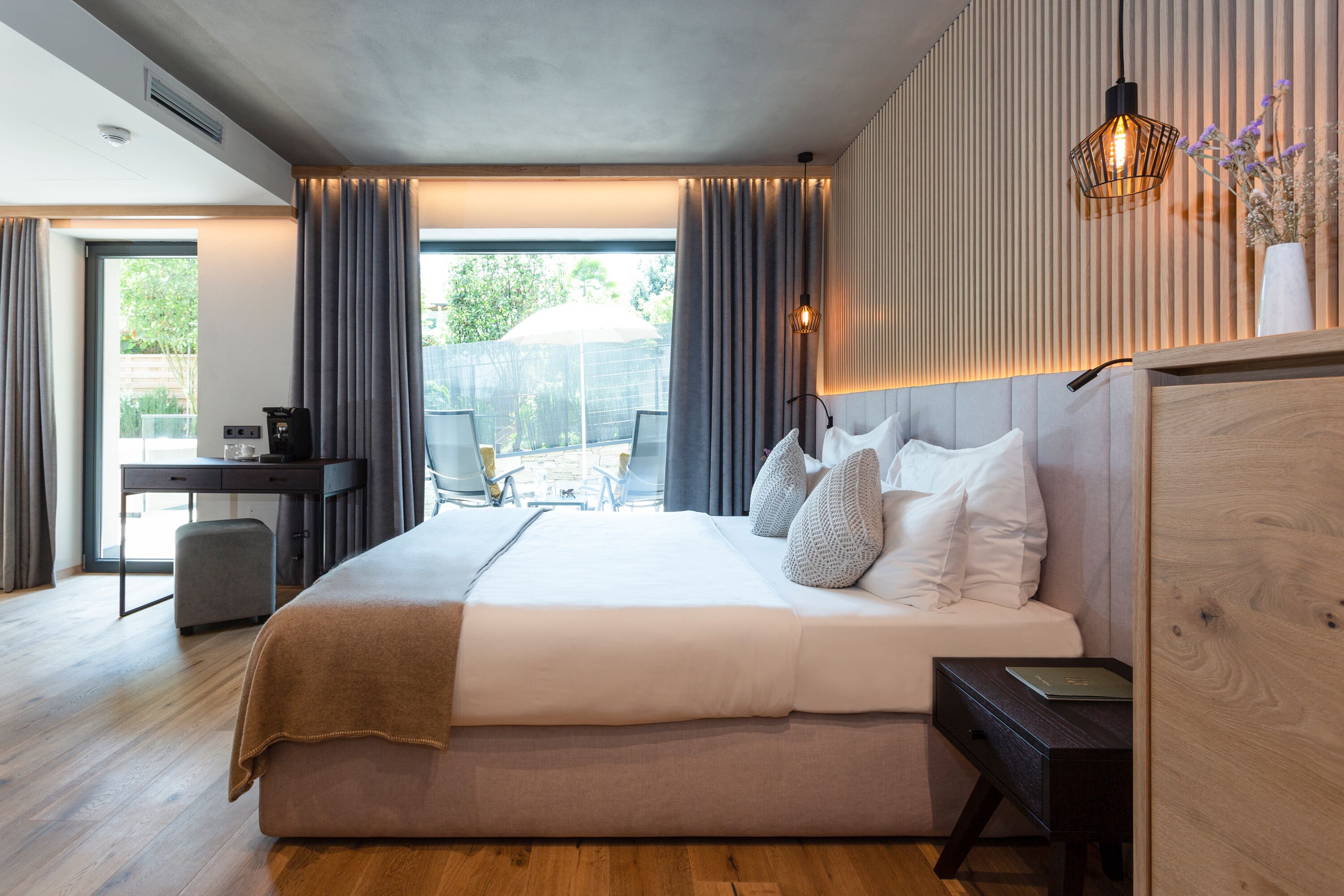 A modern hotel room with a large bed, a desk, and a view of the outdoors.