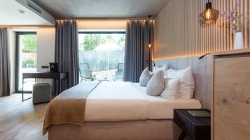 A modern hotel room with a large bed, a desk, and a view of the outdoors.
