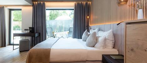 Habitación de hotel moderna con una cama grande, un escritorio y vistas al exterior.