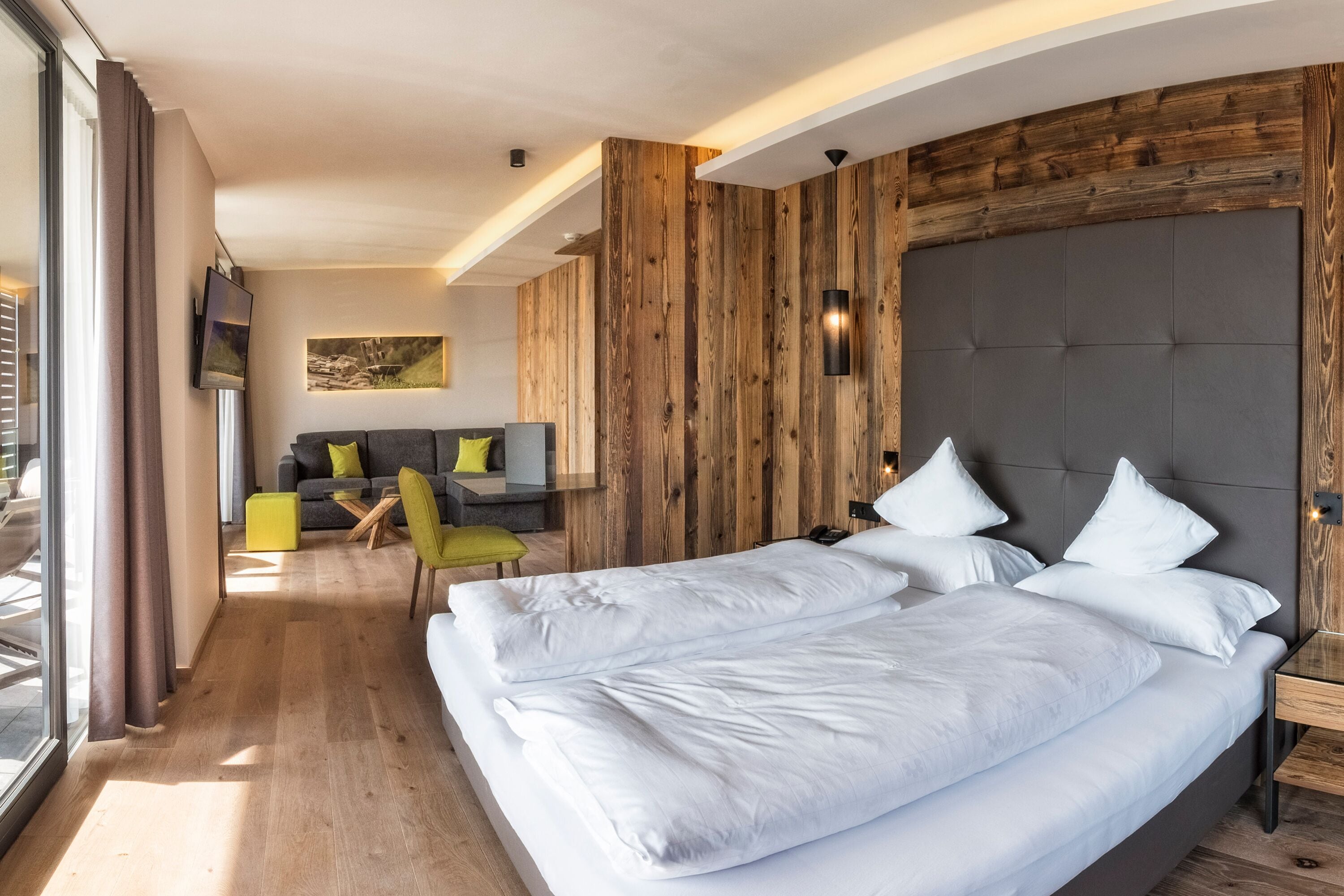 Una moderna camera d'hotel con un letto grande, una poltrona e un'area pranzo.