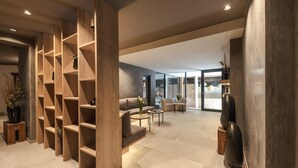 Un espacio moderno de estar con estanterías de madera, un sofá, una mesa de centro y un ventanal grande.